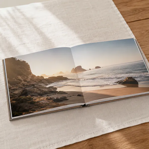 Fotolivro Premium aberto em spread panorâmico lay-flat, foto atravessando as duas páginas