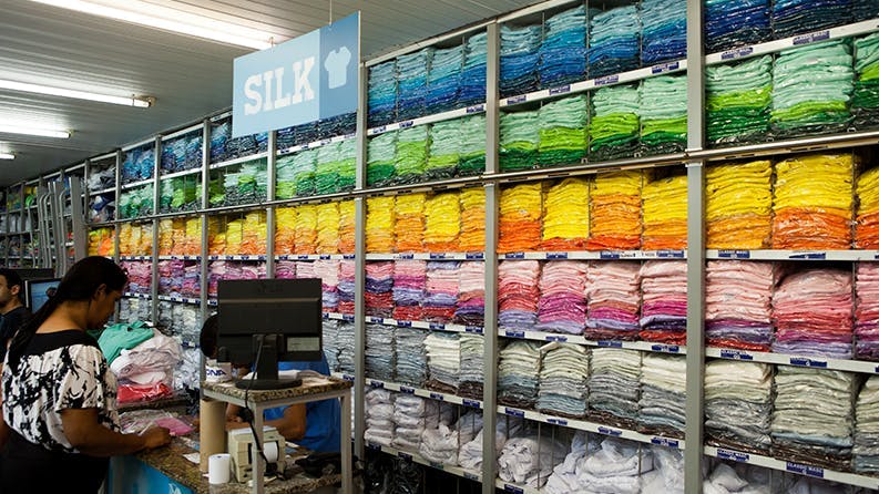 Interior da loja Dimona com várias camisas coloridas empilhadas