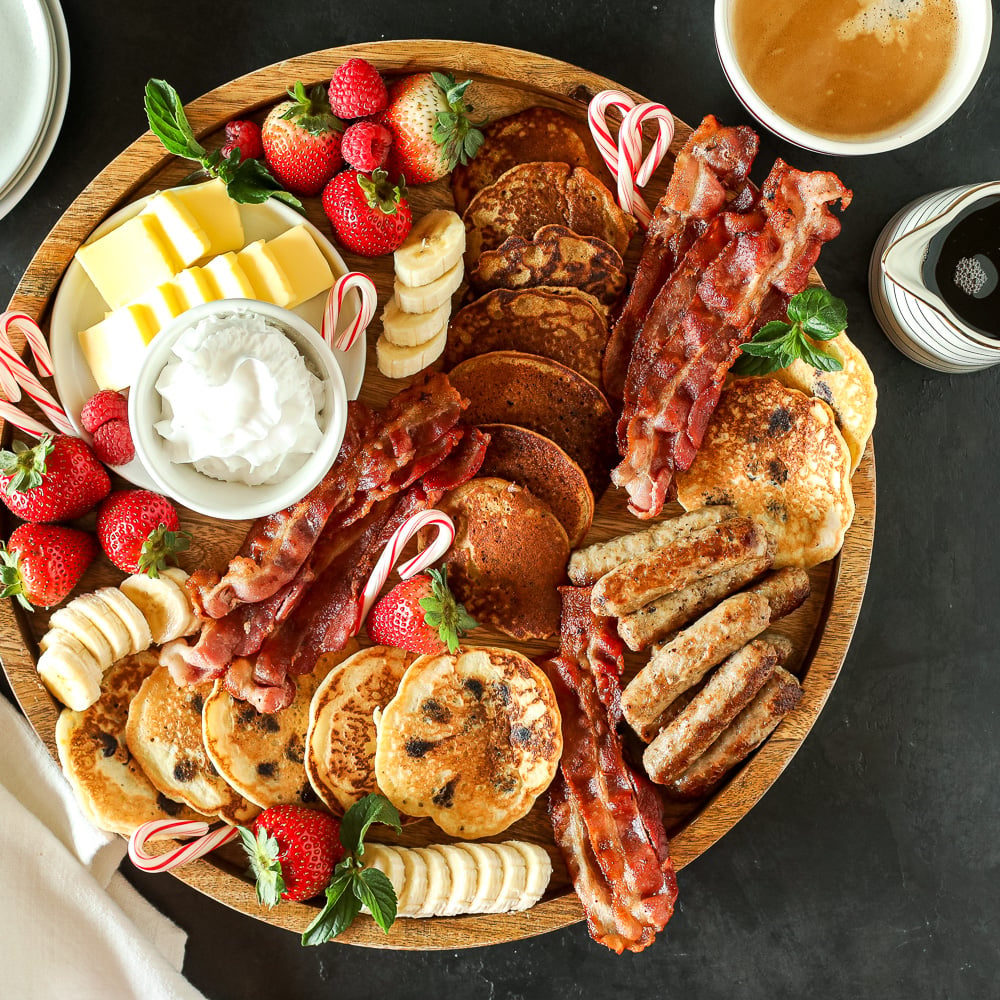 Christmas breakfast board with pancakes, bacon, berries and candy canes