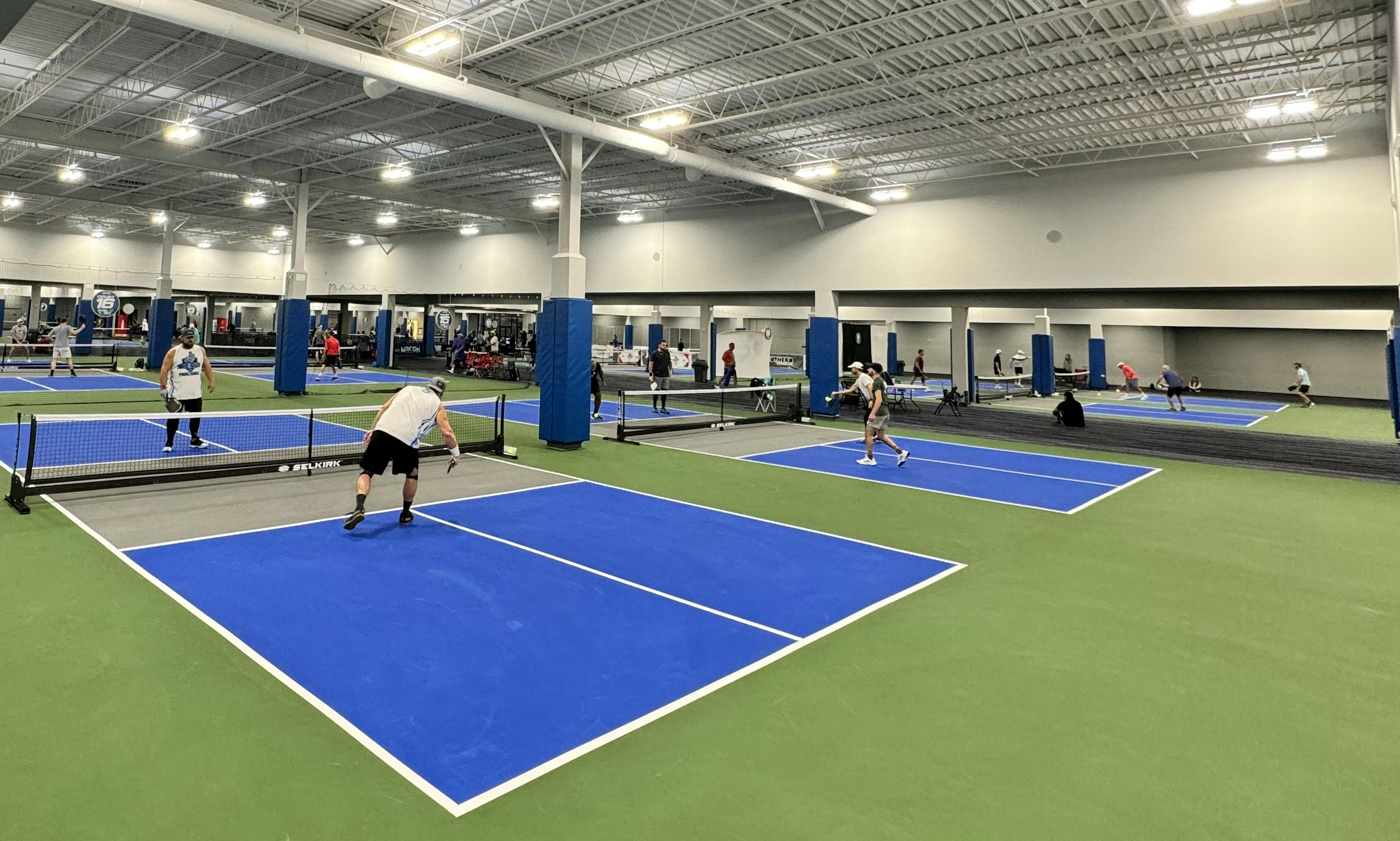 People playing pickleball on multiple courts indoors