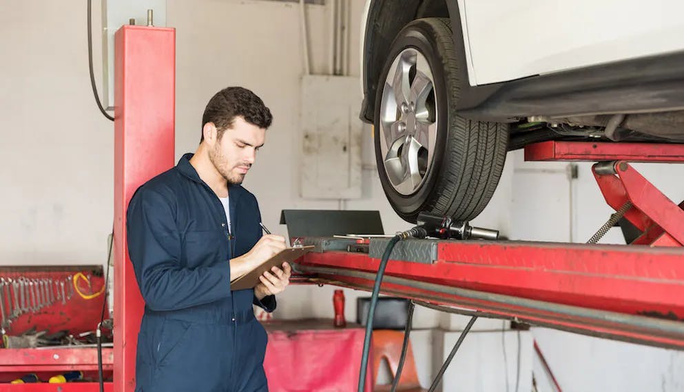 Un garagiste effectue des contrôles sur les pneus d'une voiture dans son garage
