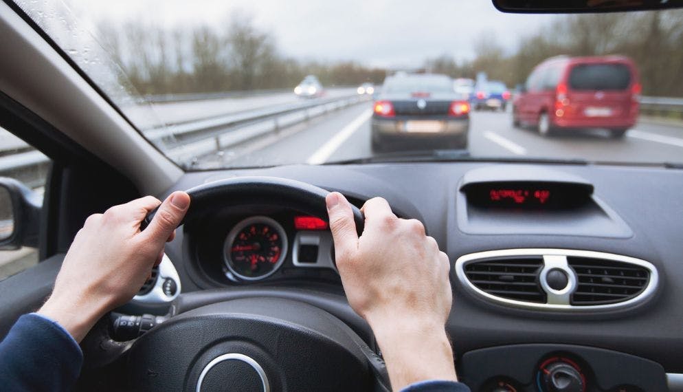 Homme qui a ses mains au volant 