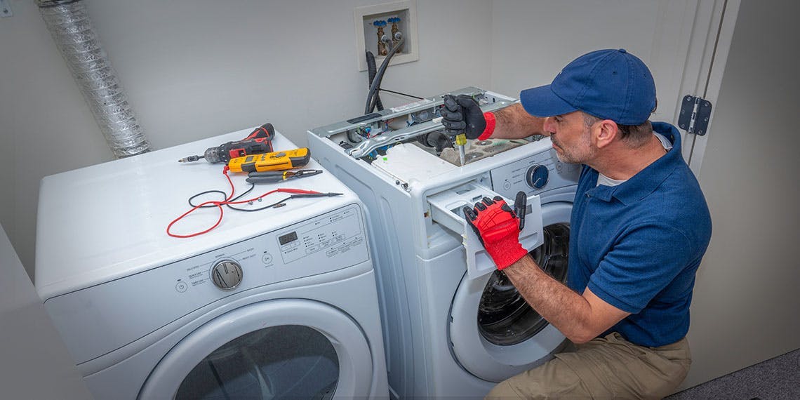 réparateur devant machine à laver en panne