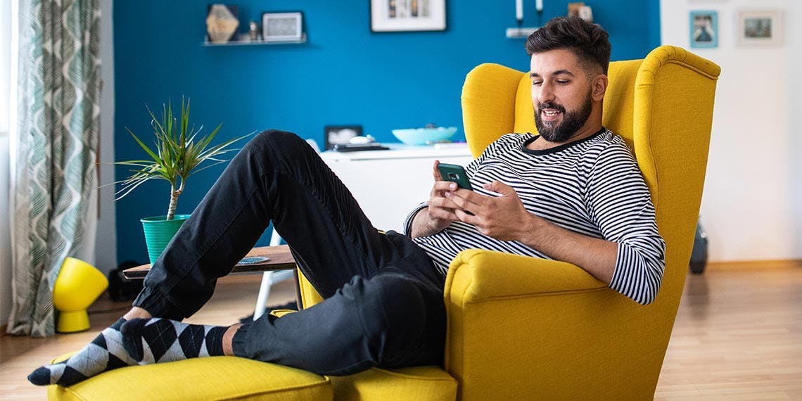 jeune homme salon fauteuil smartphone