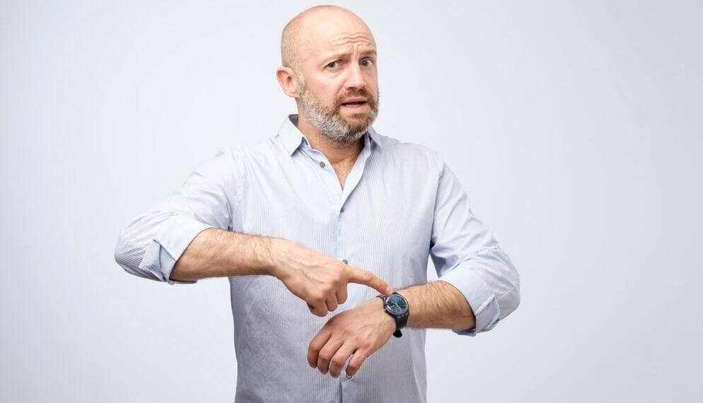 Homme impatient qui désigne sa montre