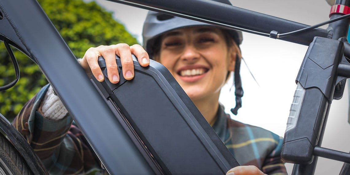 jeune femme installant batterie vélo assistance électrique