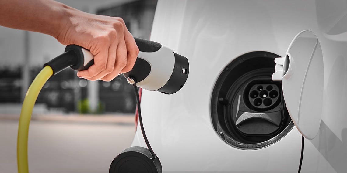 Femme débranchant un chargeur d’une prise de voiture électrique