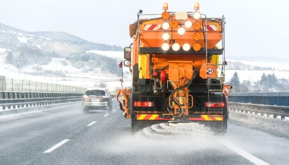 Camion qui répand du sel sur une route enneigée