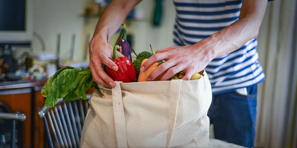 homme déballant légumes sac tissu