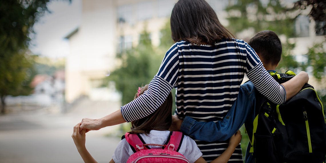 maman entourant ses enfants sur le chemin de l'école