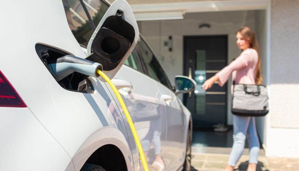Voiture électrique qui recharge devant une maison