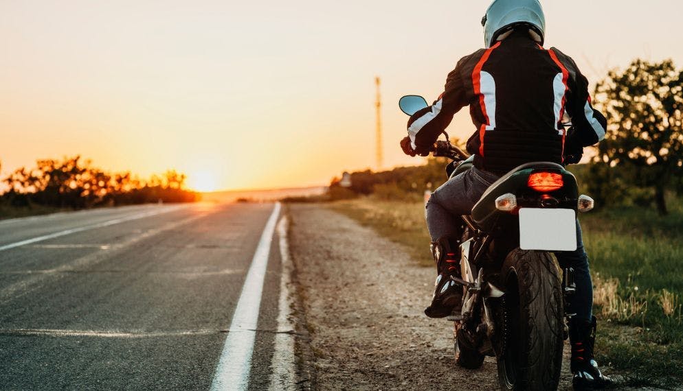 Homme sur la moto au coucher du soleil