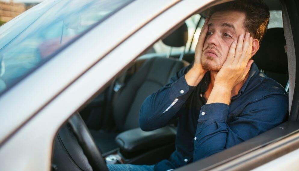 un homme dans sa voiture qui semble désespéré 