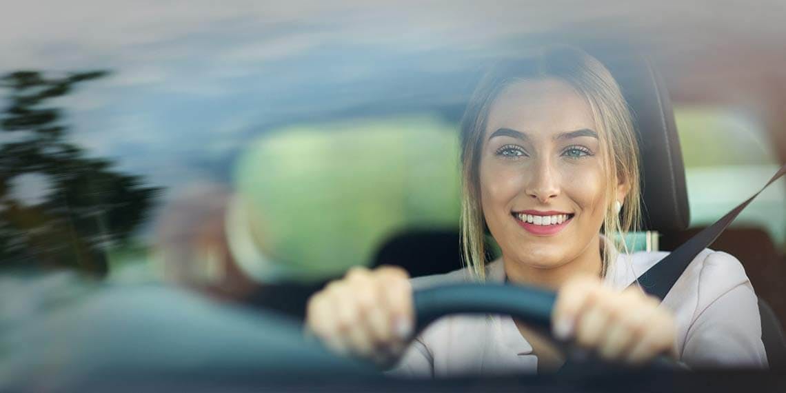 femme avec le sourire au volant d'une voiture