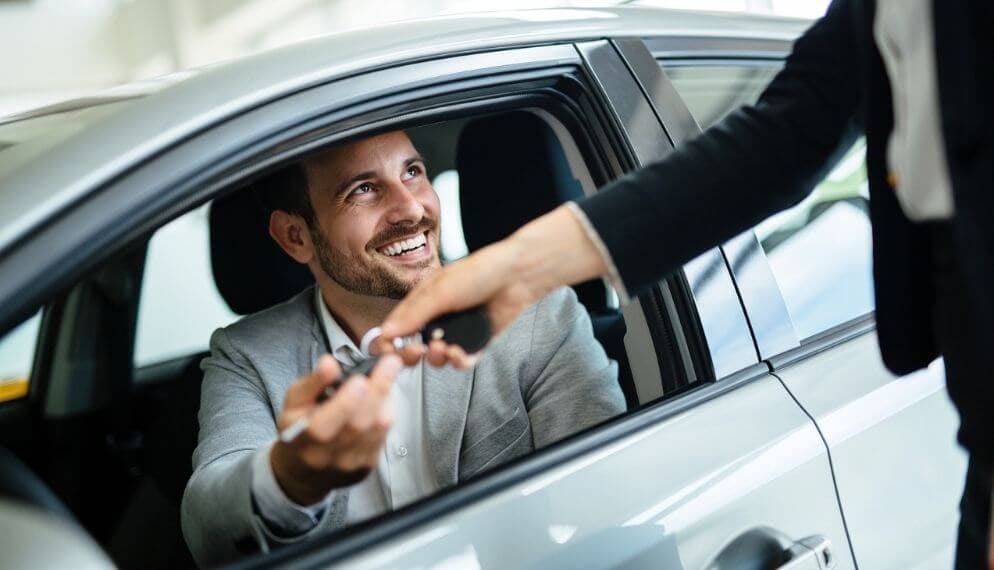 un homme à qui l'on remet les clés de sa nouvelle voiture