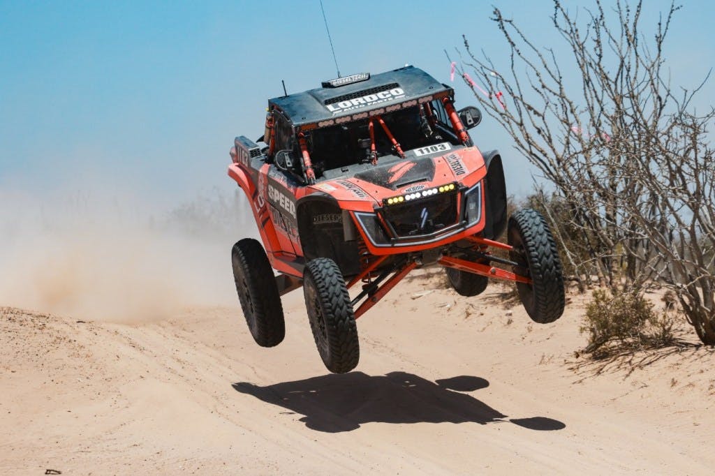 2025 speed utv baja bandit coming over a jump in a desert race.