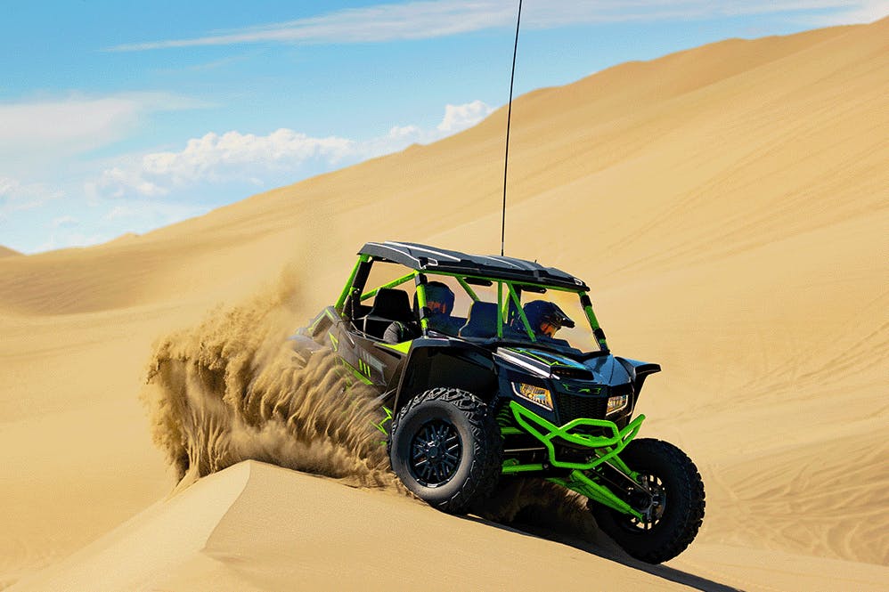 2025 arctic cat wildcat xx bursting through the desert sand like Shai-Hulud.
