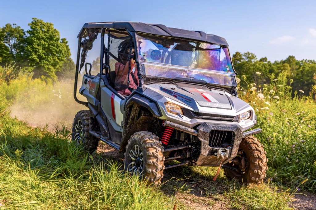 2025 honda pioneer 1000-5 driving down a dirt trail.