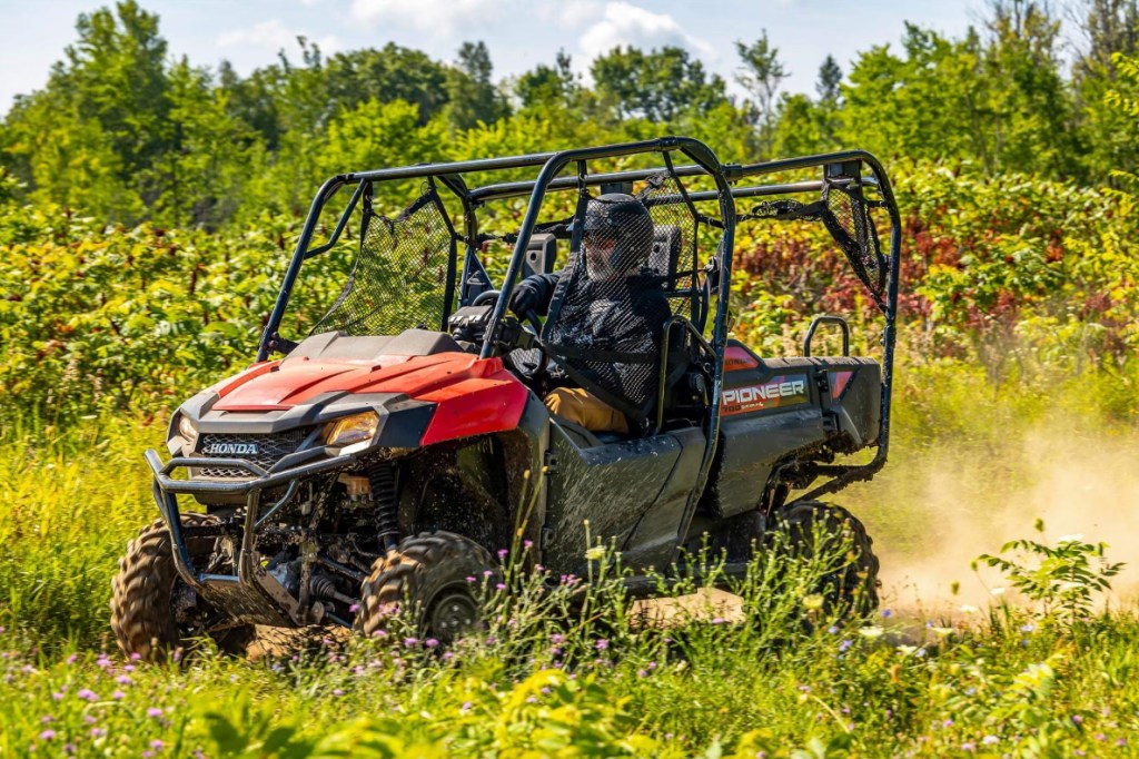 2025 Honda Pioneer 700-4 riding on a dirt trail.