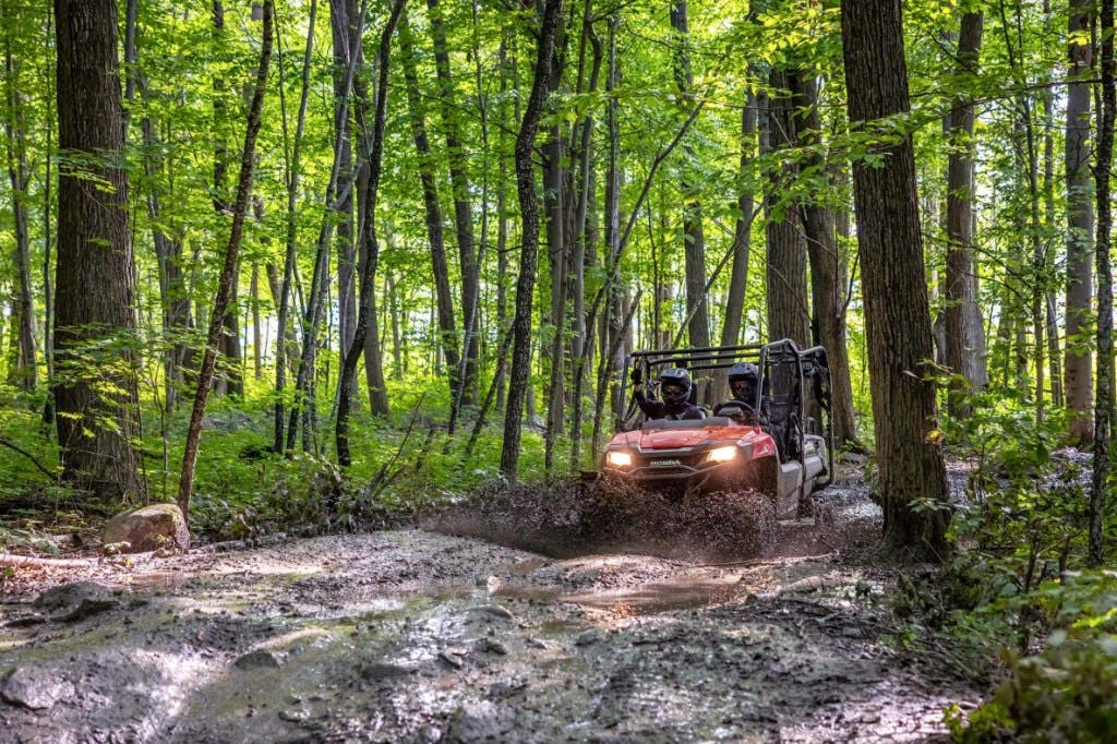 2025 Honda Pioneer 700-4 driving through mud.