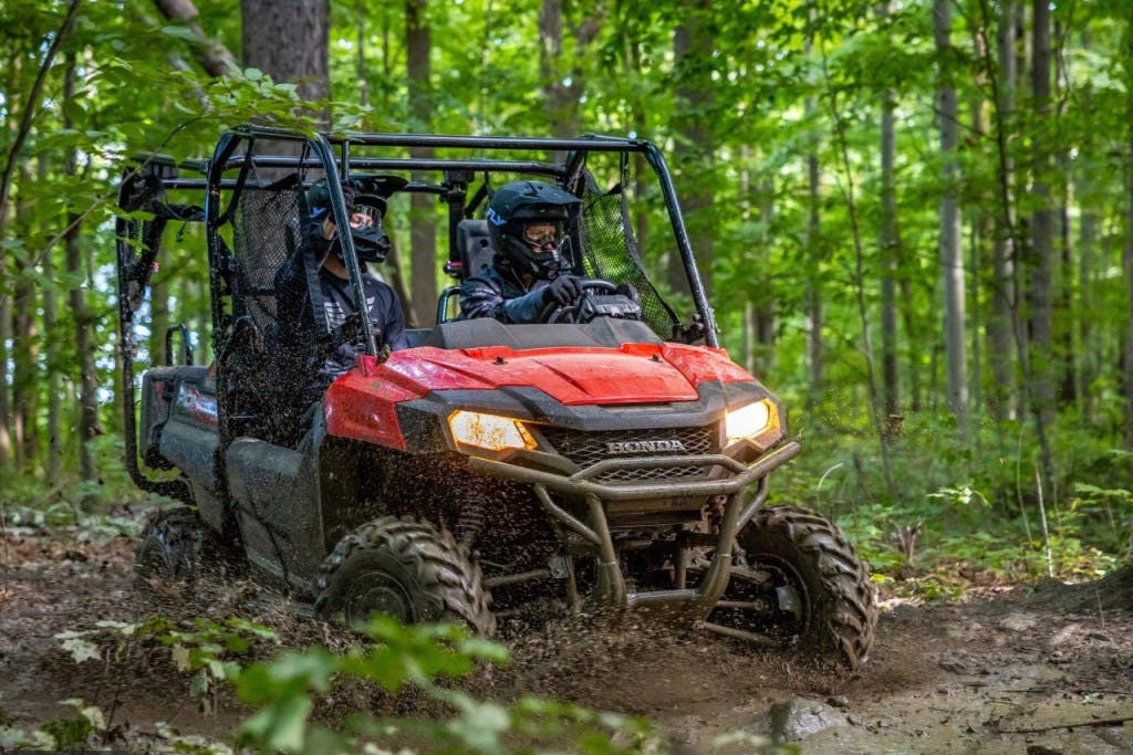 2025 Honda Pioneer 700-4 splashing through a puddle.
