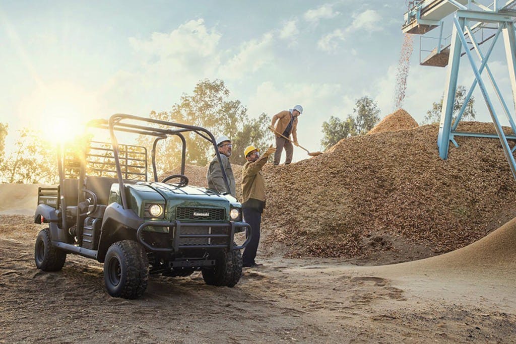 2024 Kawasaki Mule 4010 Trans looking cute beside a large pile of pine mulch.