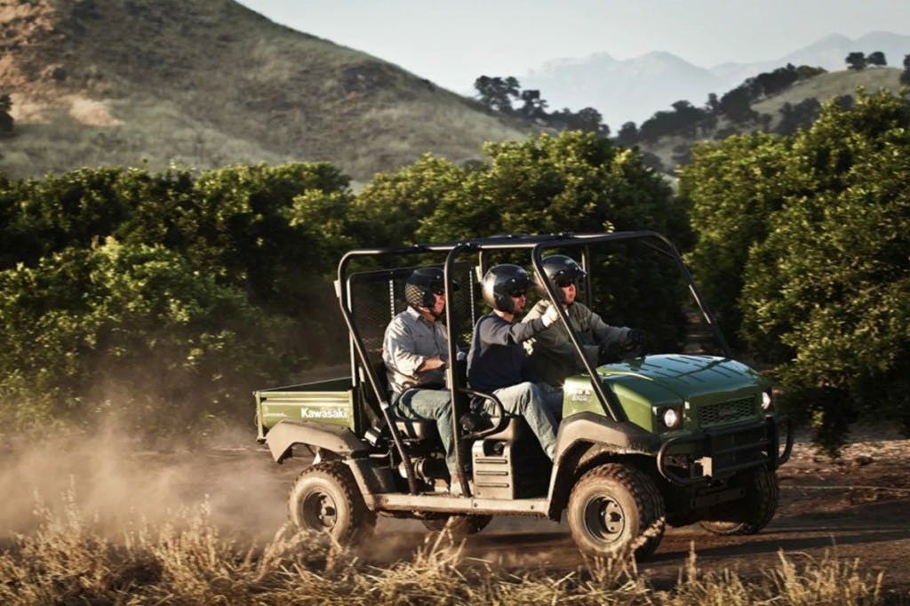2024 Kawasaki Mule 4010 Trans piloted by a middle aged man and his two clones.
