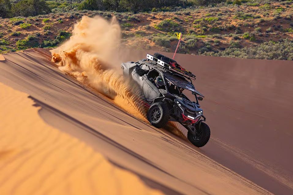 Can-Am Maverick R Max X with four passengers drifting in sand dunes.