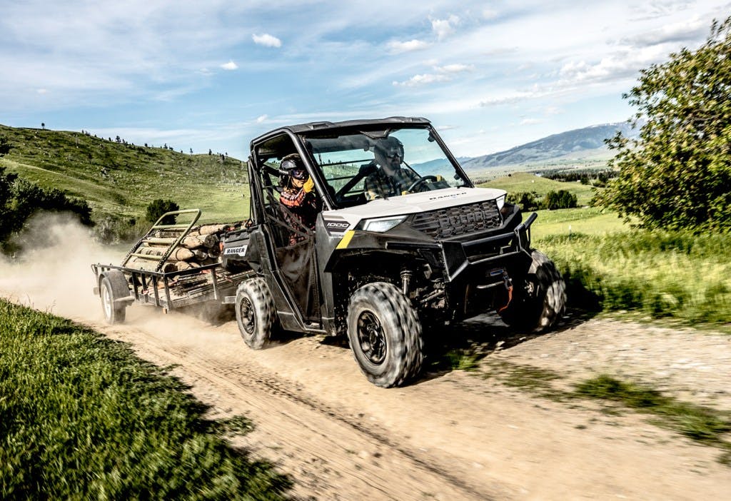 2024 Polaris Ranger Crew 1000 towing on a dirt road with mountains in the background