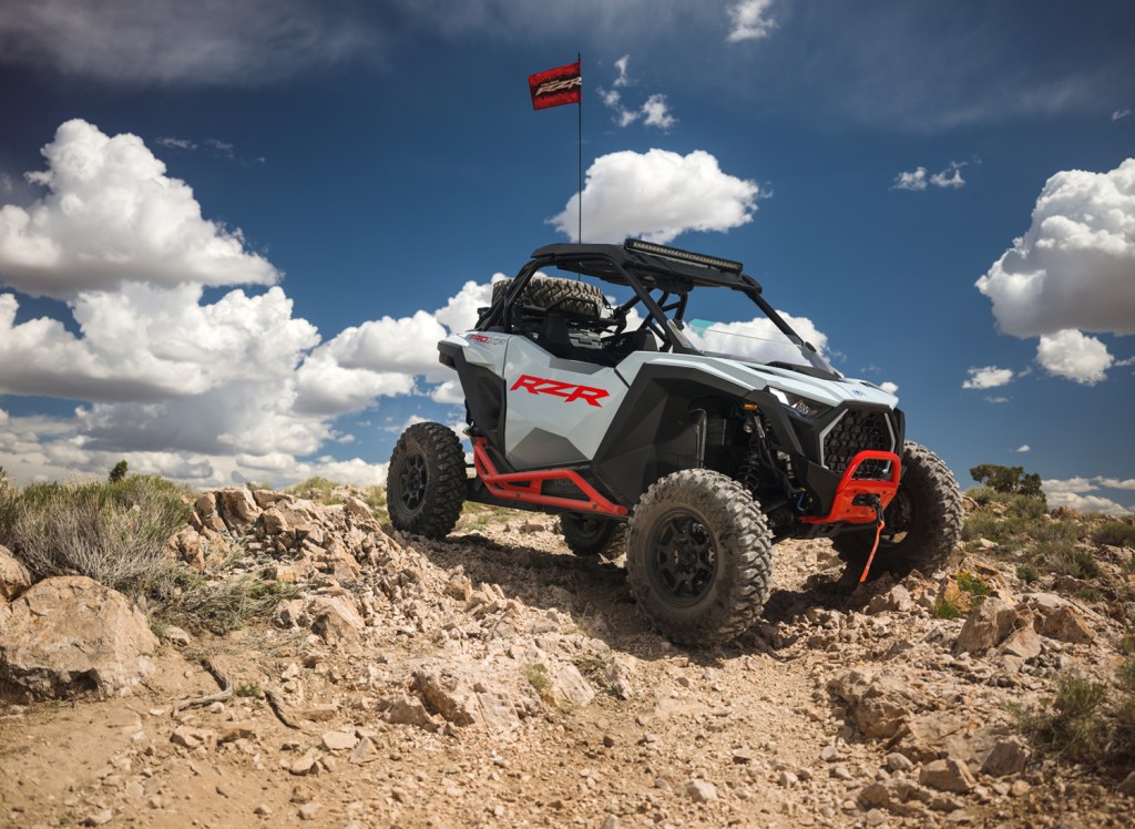 2025 Polaris RZR Pro XP Sport on a pile of rocks blue sky in background flag on top