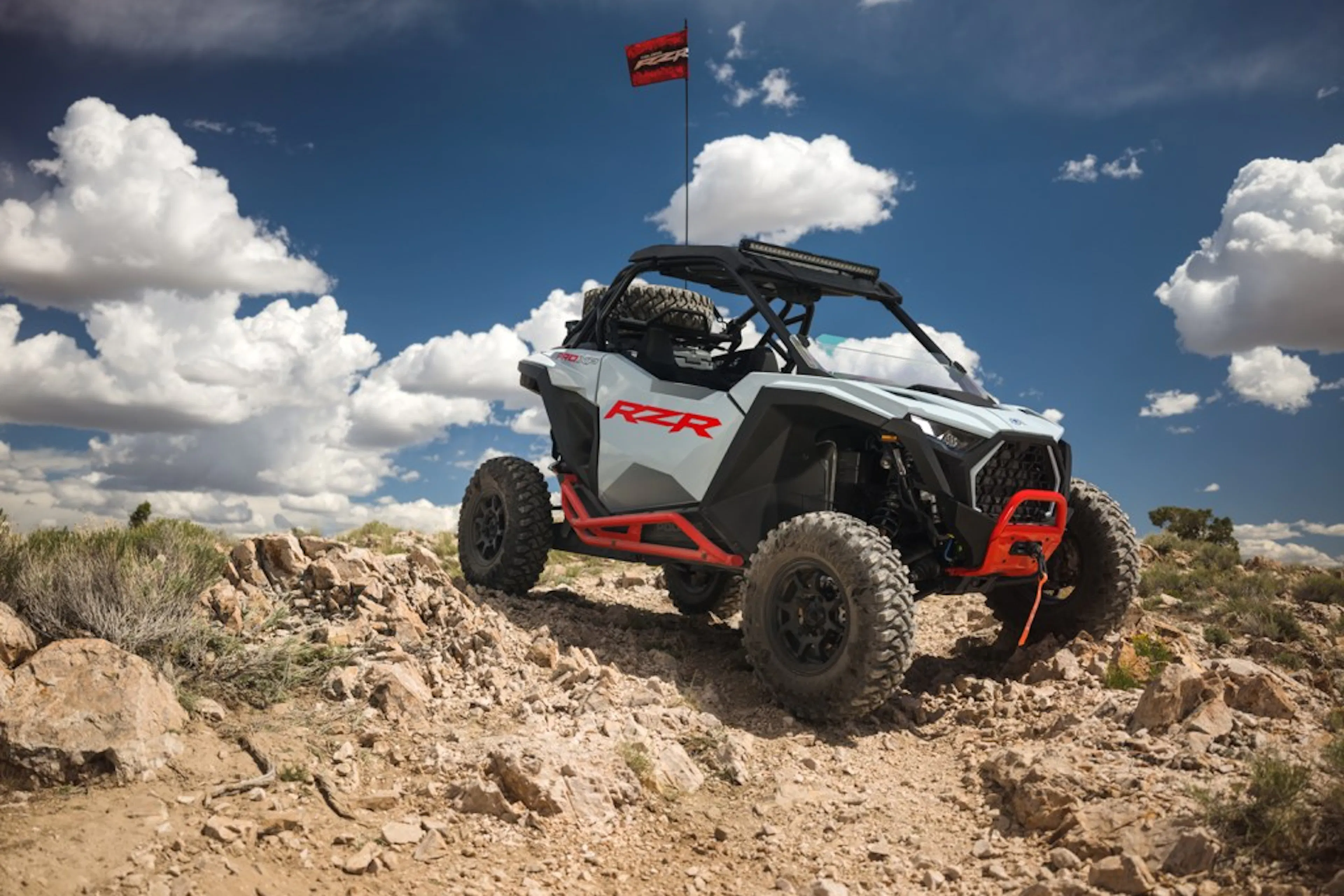 2025 Polaris RZR Pro XP Sport on a pile of rocks blue sky in background flag on top