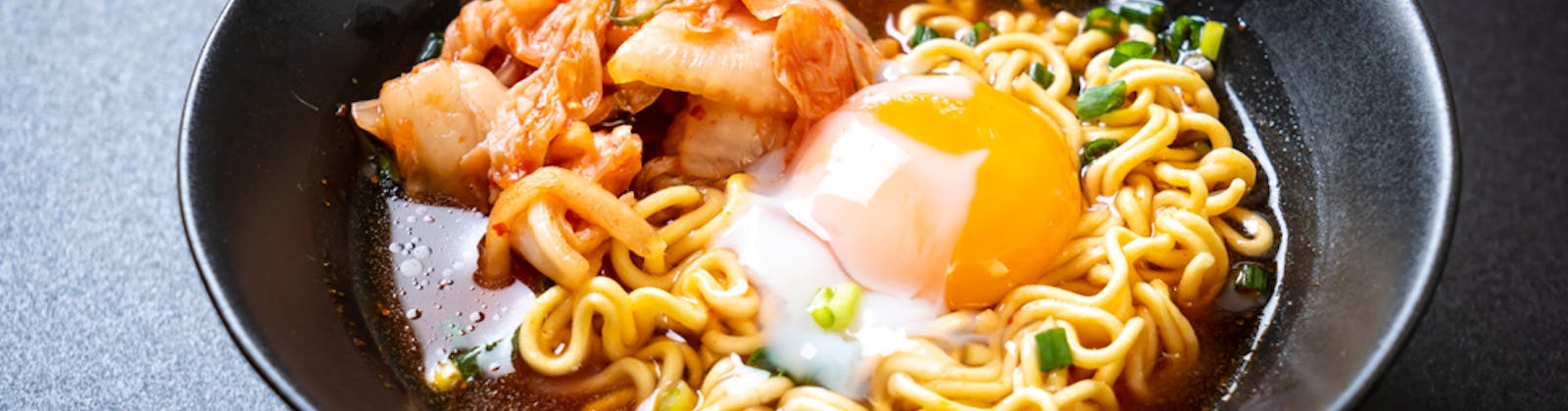 spicy noodles with kimchi and a poached egg