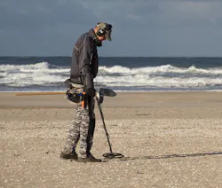 Person using metal detector on the beach shore
