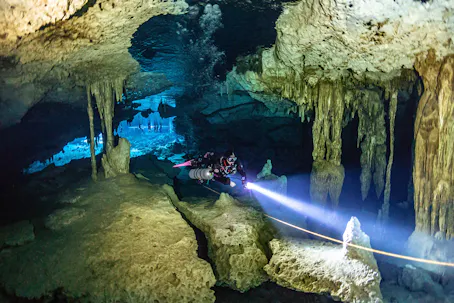 scuba diver in cavern with dive light in hand