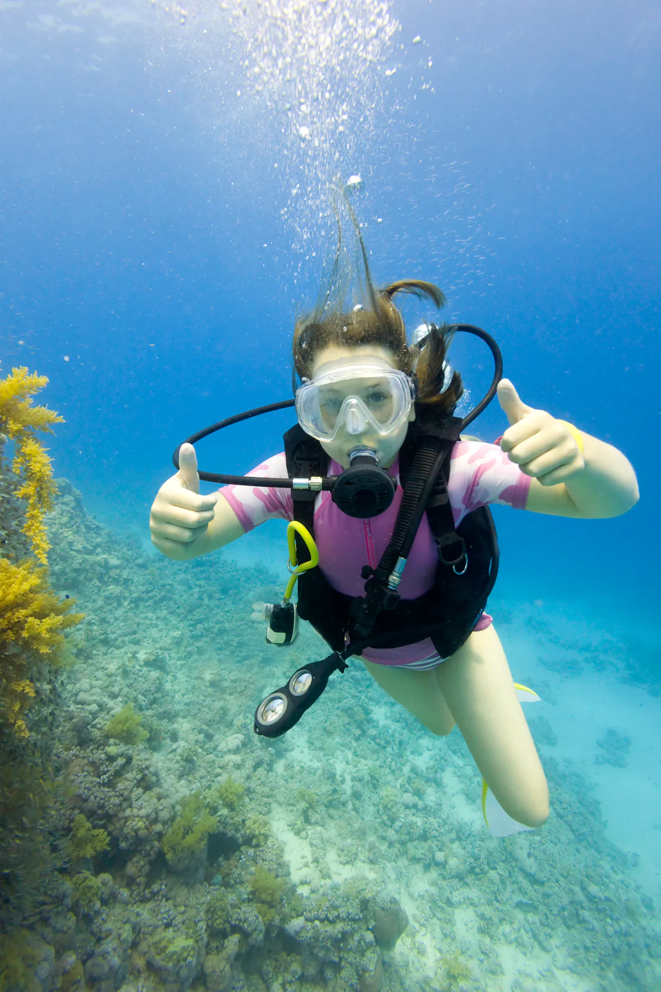 Young girl scuba diving giving two thumbs up to the camera