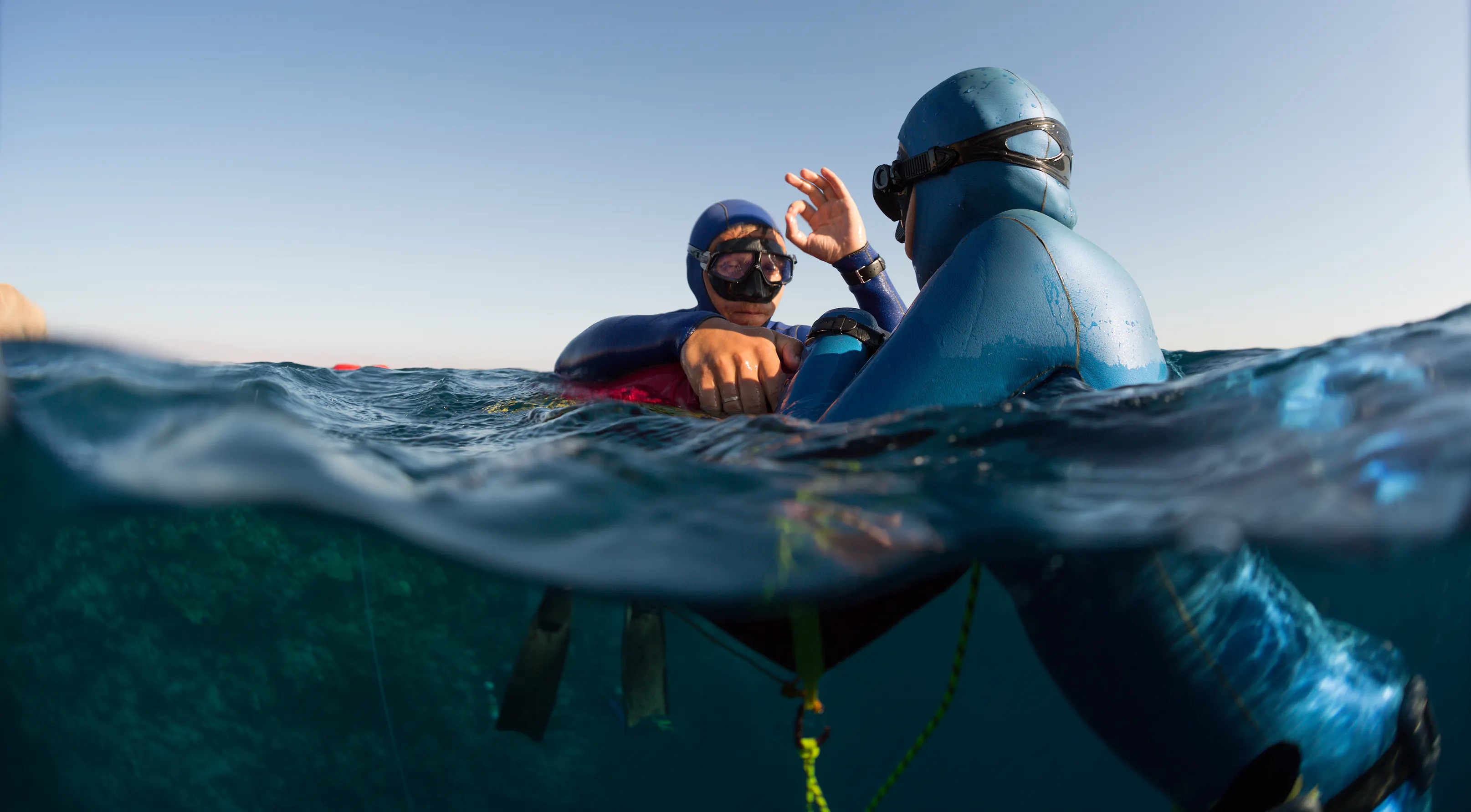 Freedivers at the surface. One letting the other know he is okay