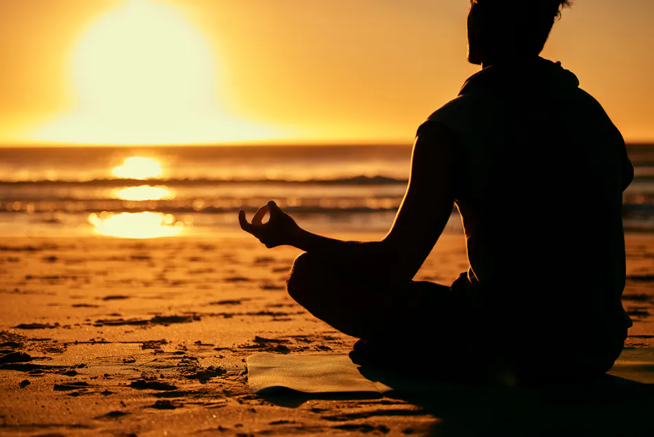 silhouette of person mediating on the beach shore