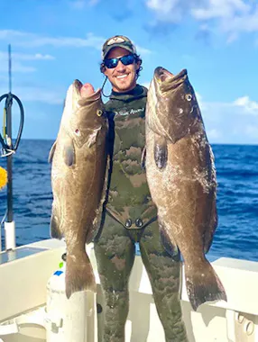Spearfisherman holding two large fish