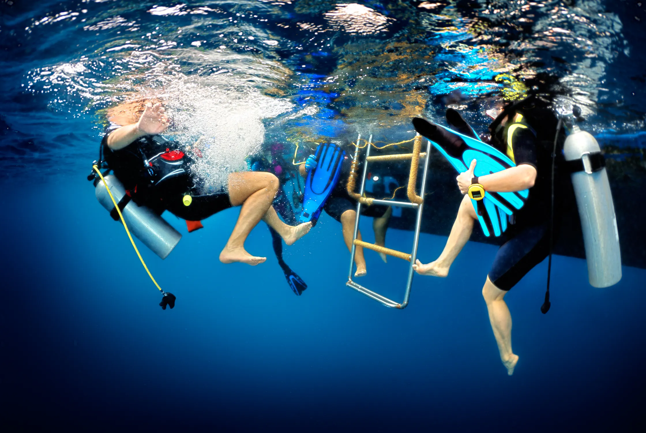 divers removing fins by charter ladder