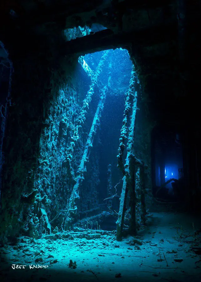 Underwater stairway inside a shipwreck with light coming from second floor