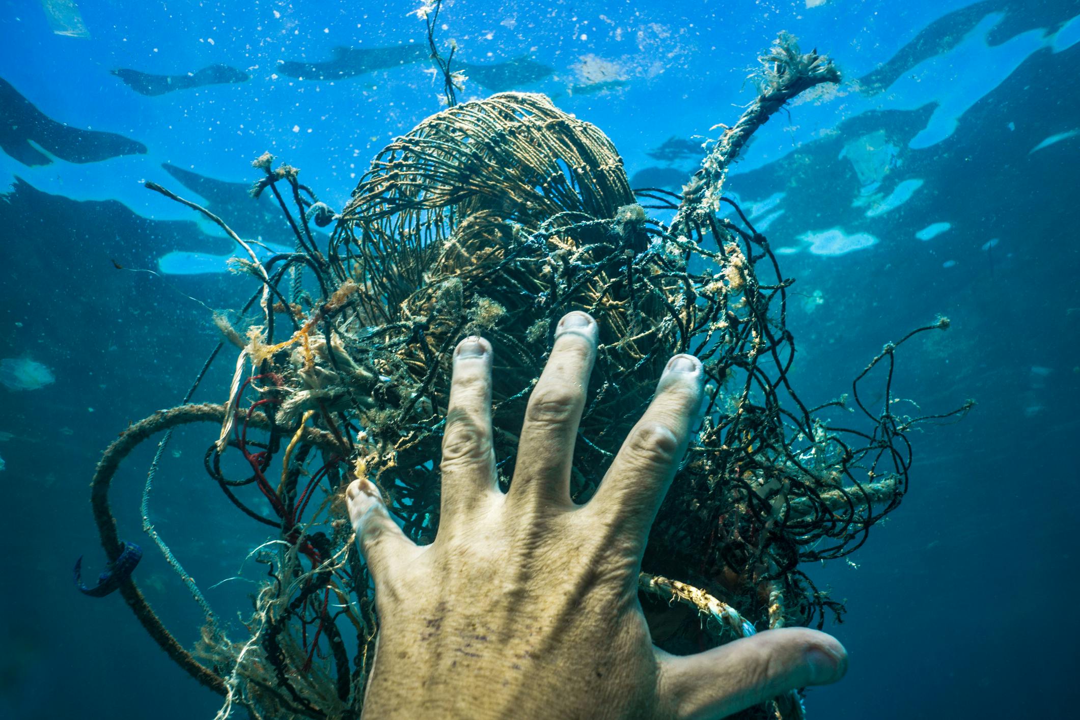 a hand reaching out for ghost nets in the water