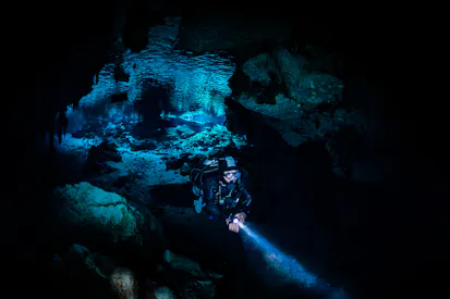scuba diver in cavern with dive light in hand