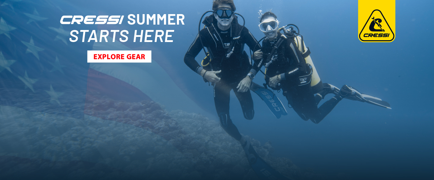  Two divers underwater posing for a picture. A USA flag faded to the left. Cressi Summer Starts Here - homepage banner.