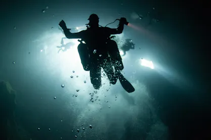 scuba diver with dive light in hand in a dark environment