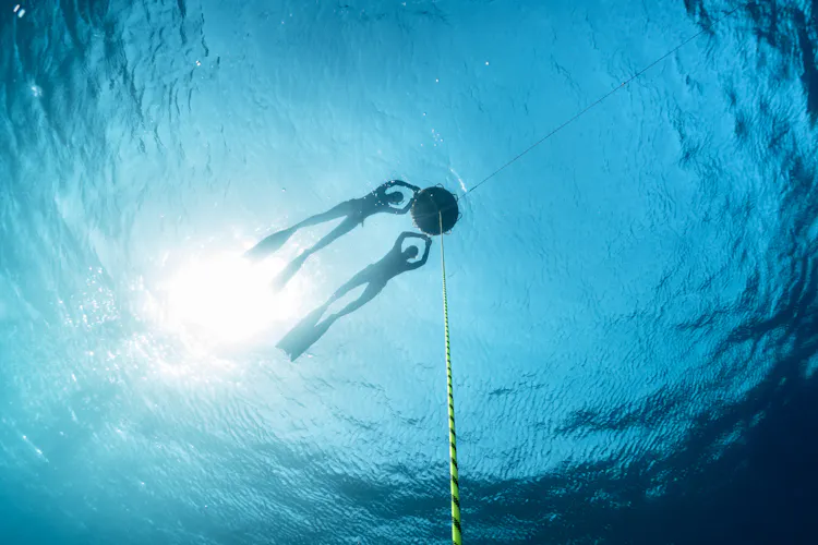 Freedivers resting, hanging on to a buoy at the ocean's surface