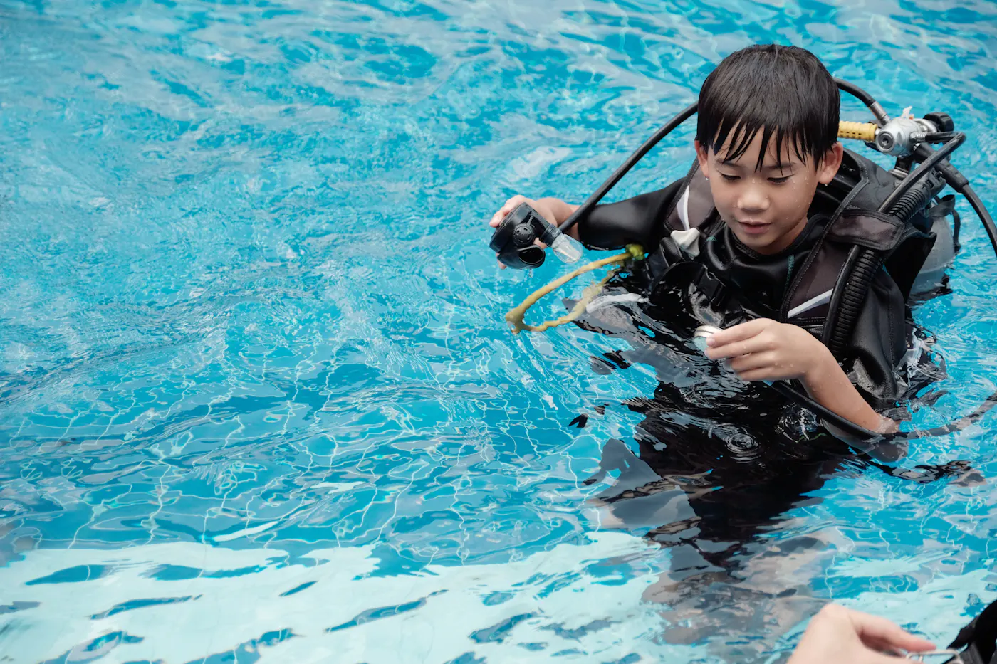 Young boy learning how to scuba dive in a pool.