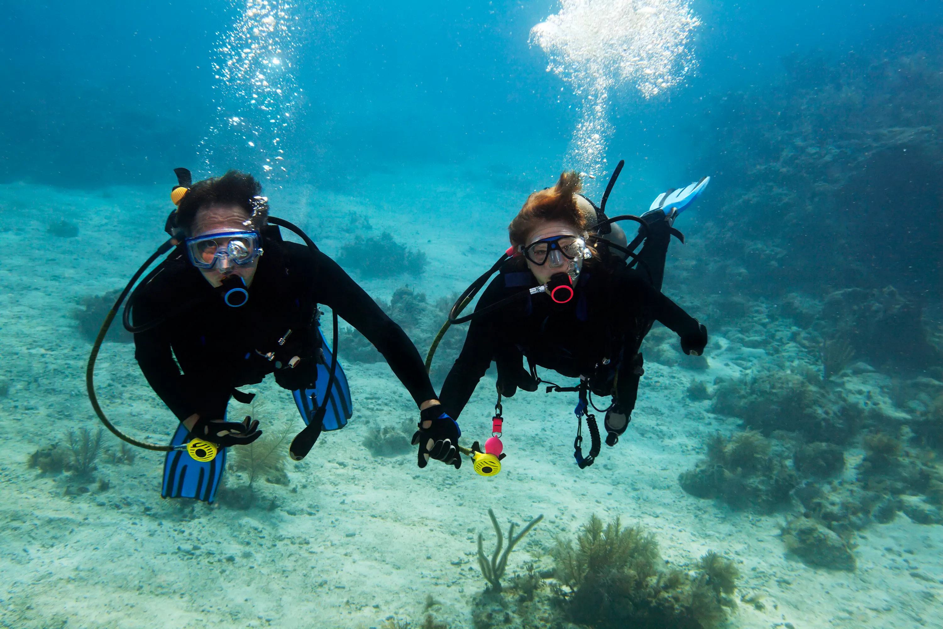 Couple scuba diving holding hands.