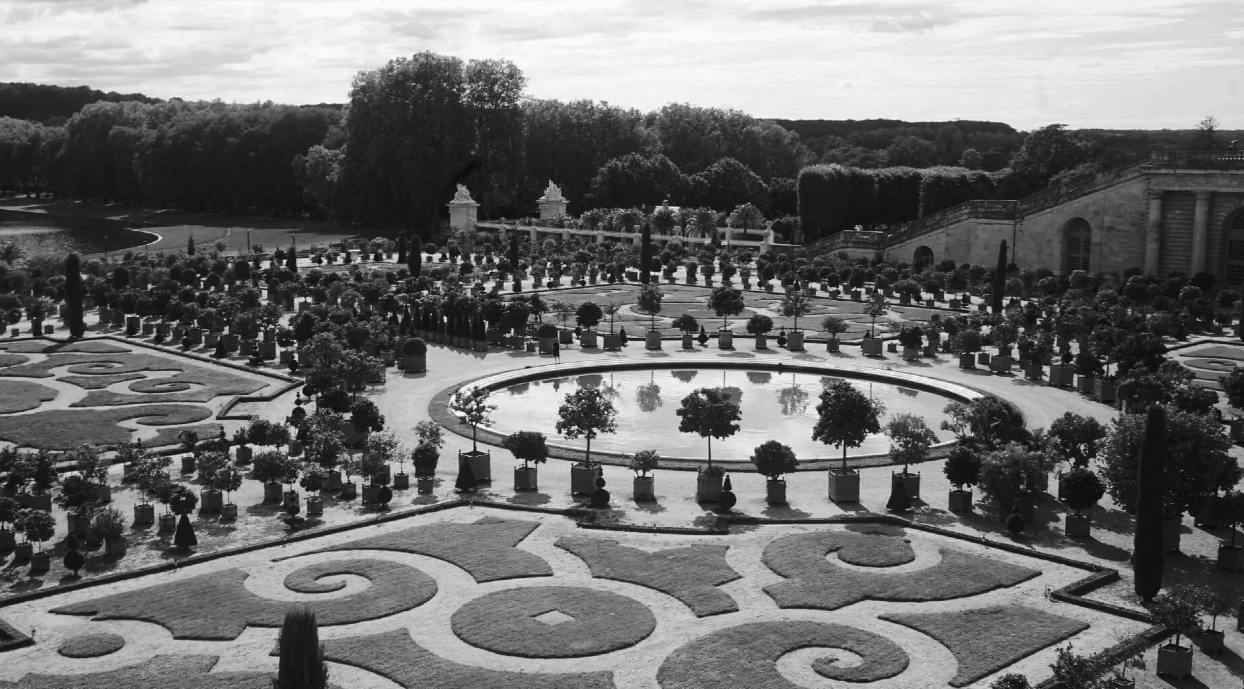 Versailles garden with a few trees and a building in the background.