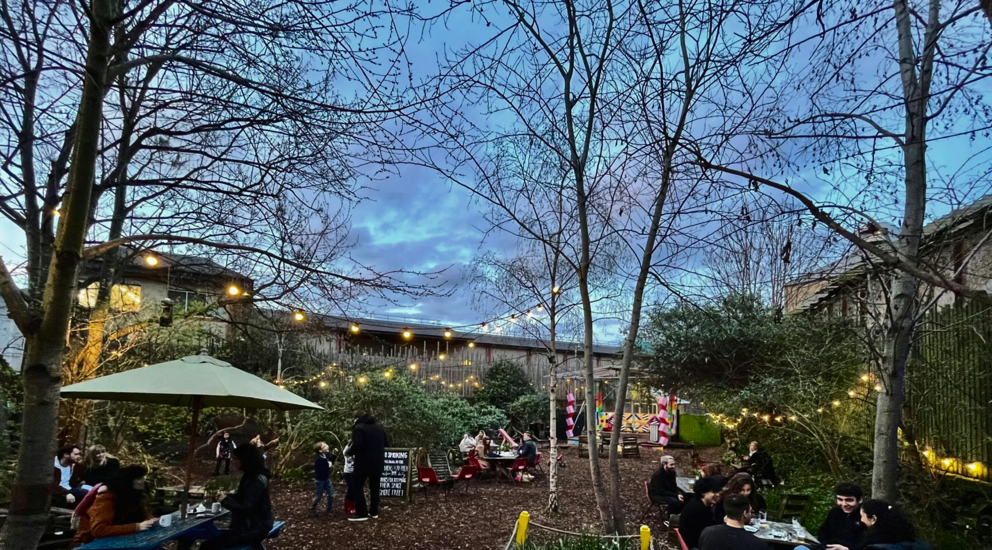 A cozy park full of people who are socializing among the trees.