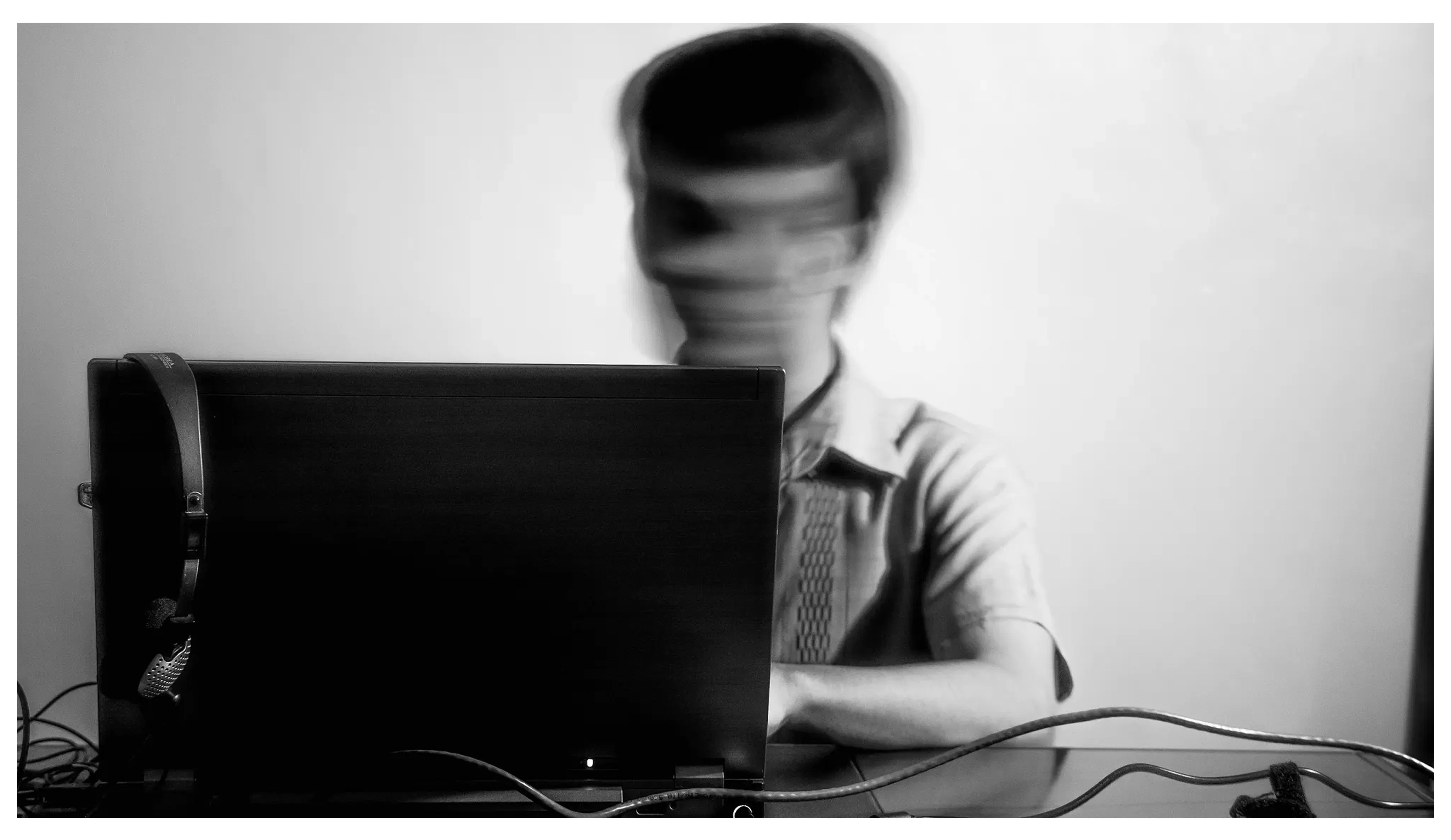 photo of a person using a computer and moving their head rapidly creating a blurry image of their face